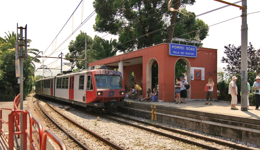 Red and white Circumvesuviana train displayed at a station, showcasing its vibrant colors and design.
