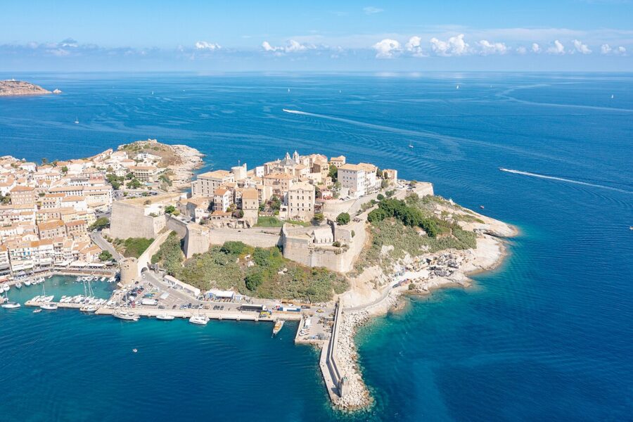 Aerial view of Calvi, a coastal town in Corsica, showcasing the Citadel and surrounding blue waters.