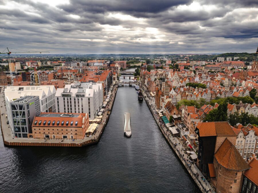 Aerial view of Gdańsk: historic and modern architecture, waterfront, canal, dramatic sky.
