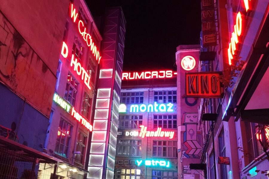 Wroclaw neon alley at night with colorful signs, KINO cinema and urban facades.