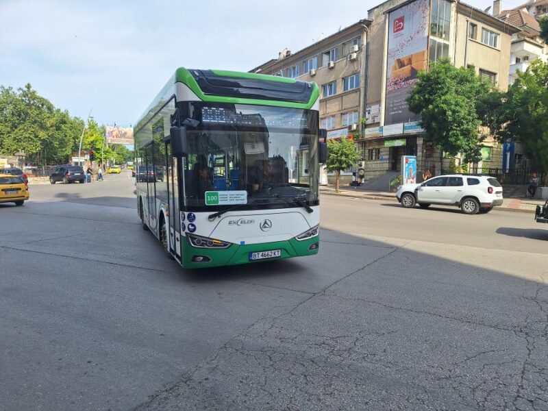 City bus approaching stop in Veliko Tarnovo on sunlit urban street.