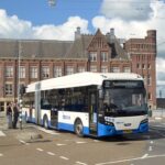 GVB articulated city bus route 22 to Muiderpoortstation turning at Amsterdam intersection with historic building.