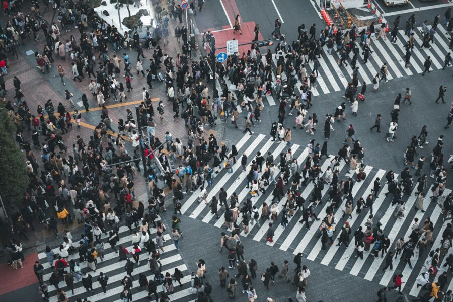 Elevated view of busy urban intersection with pedestrians in transitional outfits.