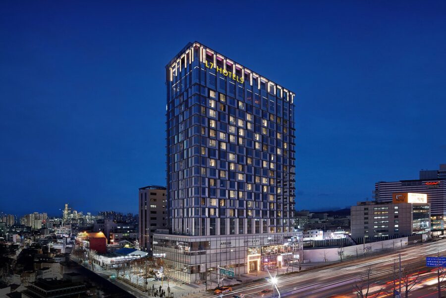L7 Hongdae by LOTTE high-rise hotel at twilight with illuminated Seoul city street.