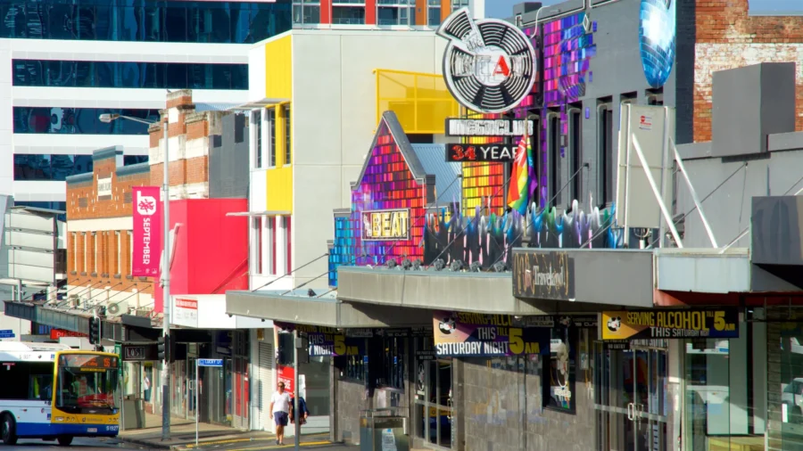Colorful Fortitude Valley nightlife district with bars, club signs, pedestrian and passing city bus.