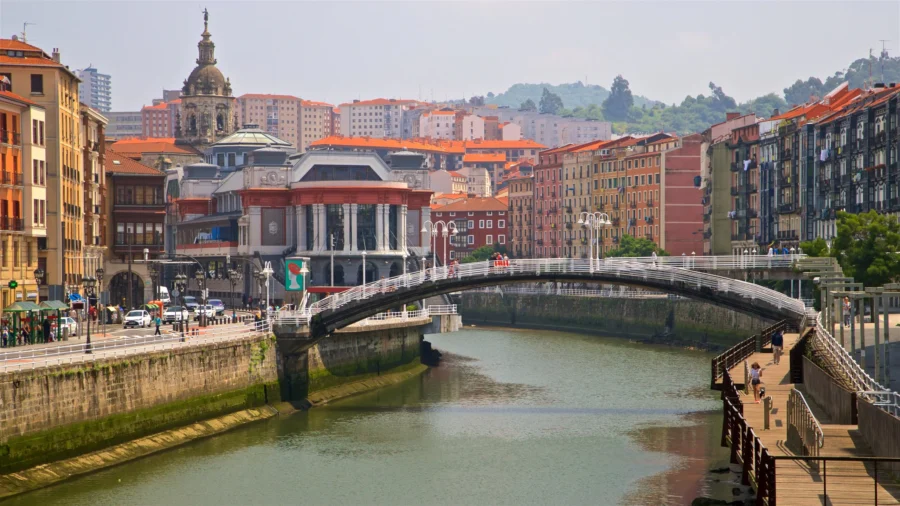 Casco Viejo Bilbao river with arched pedestrian bridge, historic buildings and riverside promenade.