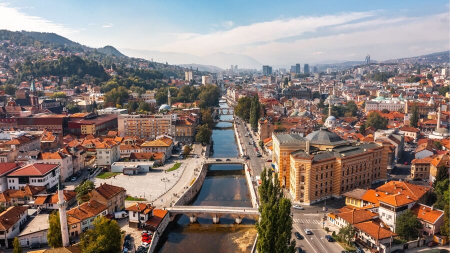 Aerial view of Sarajevo city with river, historic buildings, bridges, valley hills and mountains.