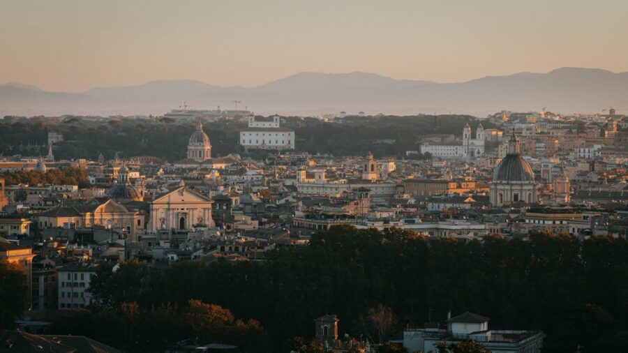 Sunlit Trastevere rooftops and domes panorama, terracotta tiles and Rome skyline.