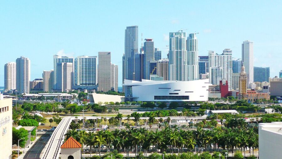 Miami skyline with modern architecture, palm trees, and vibrant cityscape under a clear blue sky.