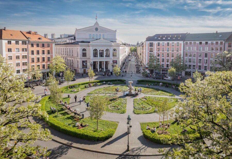 Aerial view of circular city square garden with fountain, benches, and surrounding classical buildings.