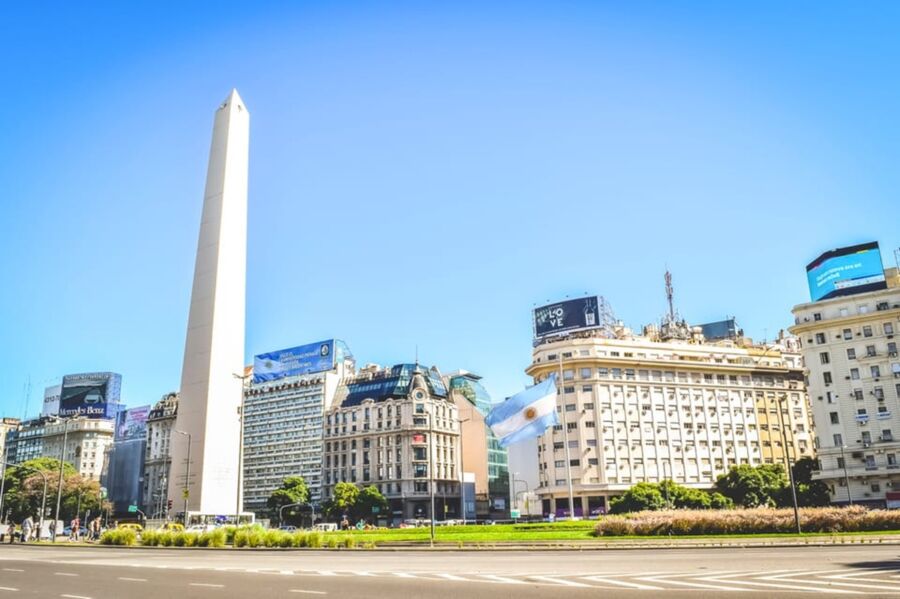 Bustling Buenos Aires scene with Obelisco, diverse architecture, greenery, and vibrant commercial activity.
