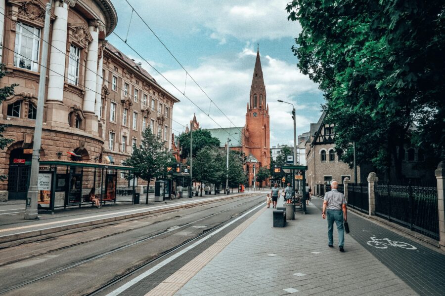 Poznan, Poland street with tram tracks leading to red-brick church spire and tram stop.