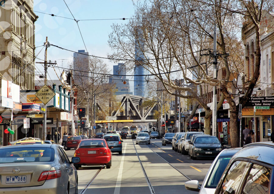 Busy Swan Street tram tracks, city traffic, historic shopfronts and modern downtown skyline in winter.
