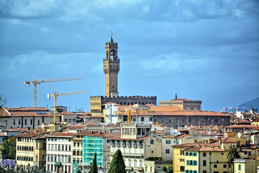 Florence cityscape featuring historical Palazzo Vecchio skyline and modern construction cranes.
