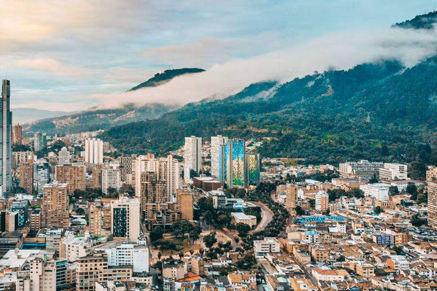 Urban cityscape with diverse architecture, mountains, mist, and parks in lush Colombia.