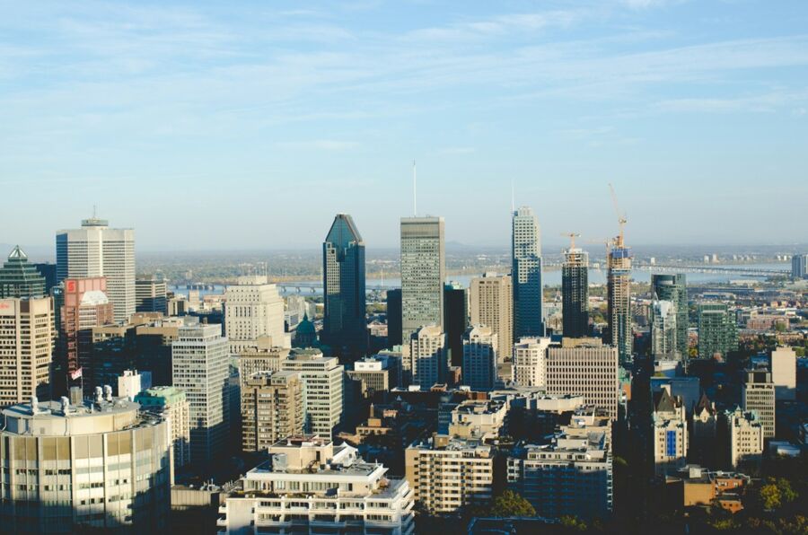 Bustling city skyline with skyscrapers, diverse architecture, clear sky, and ongoing construction.