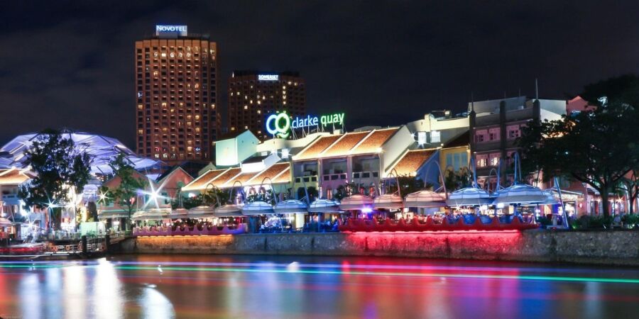 Clarke Quay Singapore: vibrant nightlife scene with riverside dining, colorful lights, and skyline views.