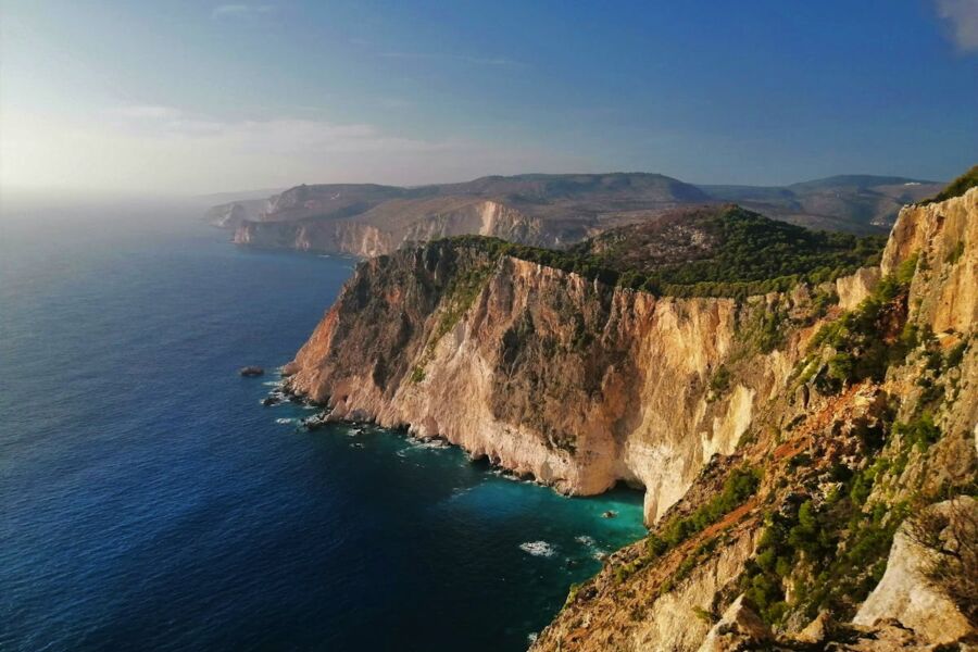 Rugged coastal cliffs meet tranquil ocean under soft sunlight, showcasing natures serene beauty.