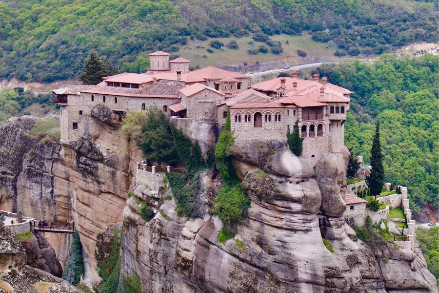Varlaam Monastery on Meteora cliff in Greece, historic stone complex with terracotta roofs.