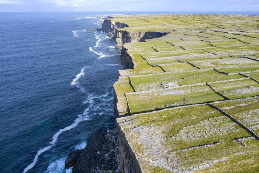 Aran Islands dramatic sea cliffs and patchwork stone-walled fields along rugged Atlantic coastline.