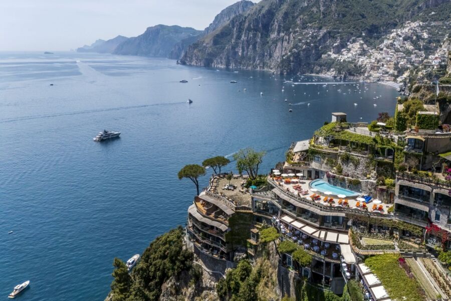Aerial view of luxurious coastal resort on Amalfi Coast with Mediterranean Sea backdrop.