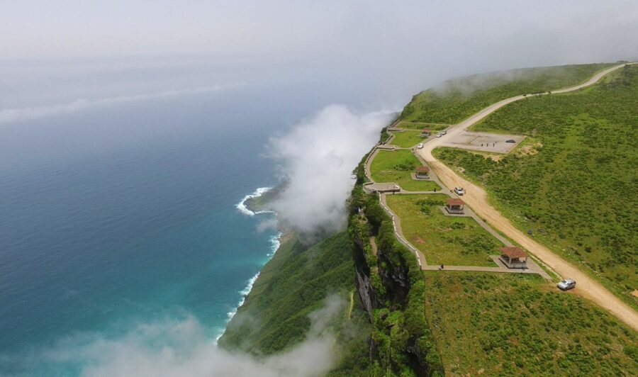 Foggy coastal cliff walkway overlooking turquoise ocean, misty sea cliffs, scenic khareef landscape.