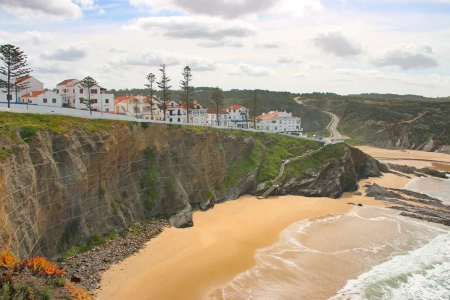 Cliffside Portuguese village and sandy beach with whitewashed houses and red-tiled roofs.