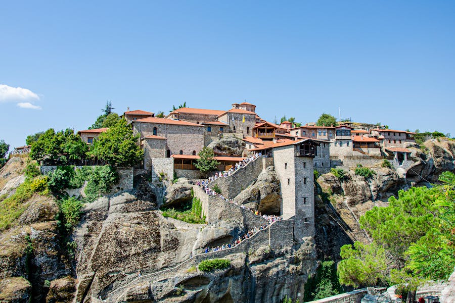 Meteoras Great Meteoron monastery perched on Greek cliff with stone pathway and terracotta roofs.