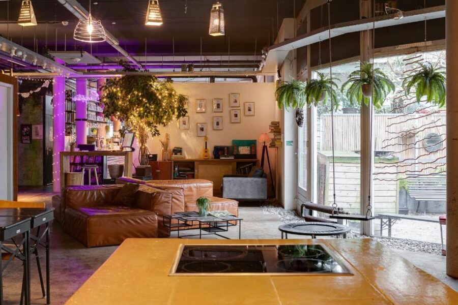 Interior of ClinkMama, Amsterdam Lounge, showcasing a living room with a table, chairs, and vibrant plants.