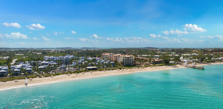 Tranquil beach scene with sailboats, turquoise waters, golden sands, and charming coastal resorts.