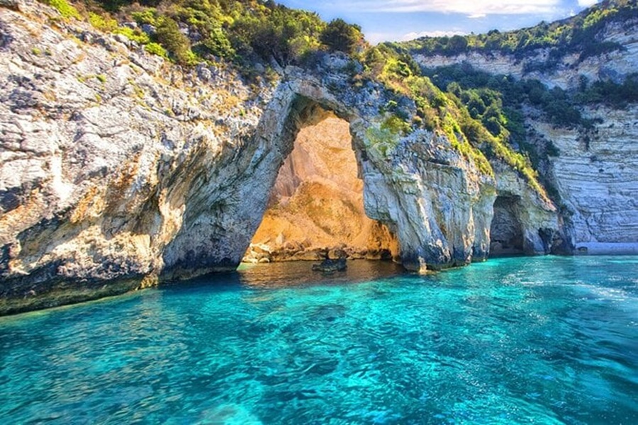 Stunning coastal rock arch with clear turquoise waters and lush greenery in Paleokastritsa.