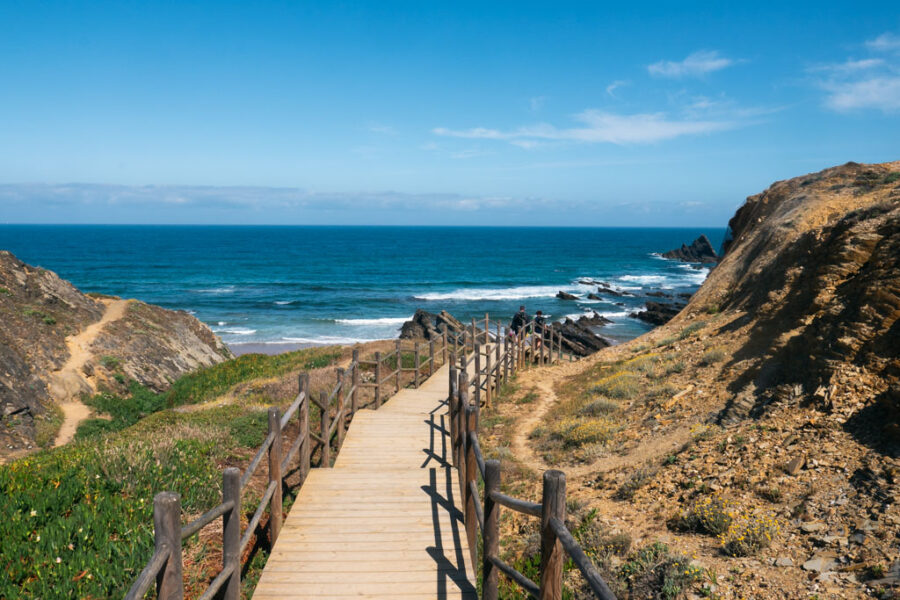 Rota Vicentina coastal boardwalk overlooks rocky cliffs and turquoise Atlantic ocean.