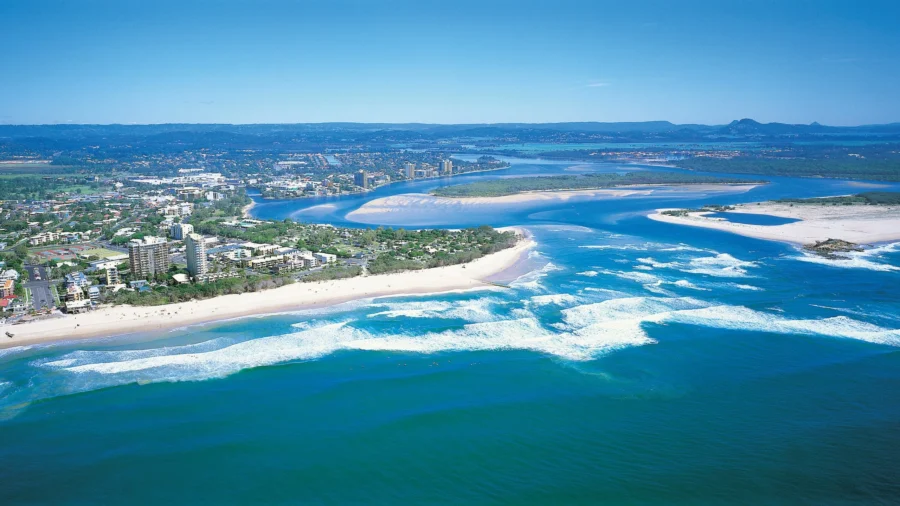 Aerial view of Maroochydore beach, turquoise ocean waves, coastal city skyline and river estuary.