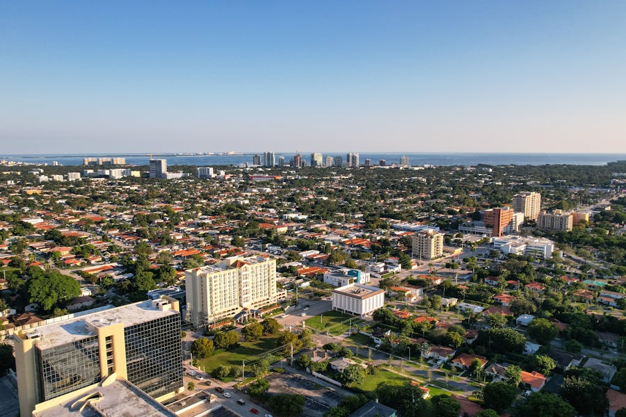 Aerial view of coastal city with waterfront skyline, residential neighborhoods, and mid-rise buildings.