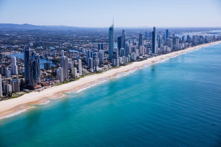 Aerial view of Gold Coast beachfront skyline, tall skyscrapers along sandy beach and turquoise ocean.