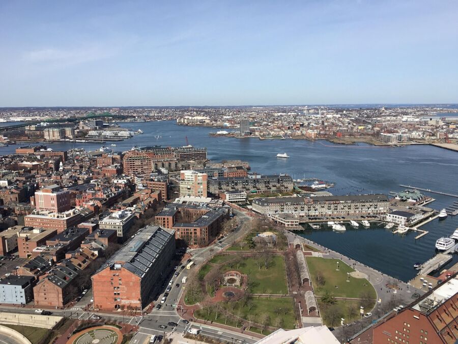 Aerial view of Boston waterfront including historic buildings, marina, and skyline.