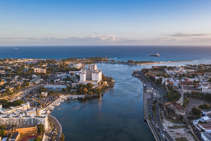 Aerial view of coastal city with river, ocean, diverse architecture, and vibrant urban life.