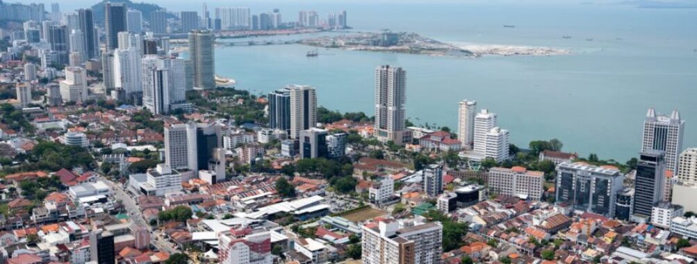 Aerial view of modern coastal city skyline with bay, high‑rise buildings and waterfront development.