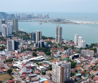 Aerial view of modern coastal city skyline with bay, high‑rise buildings and waterfront development.