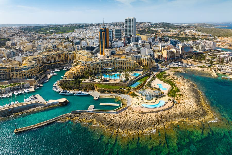 Scenic aerial view of Maltas coastal city with luxurious buildings and vibrant waterfront.