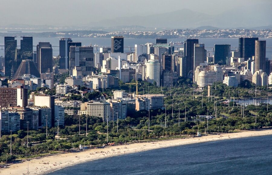 Aerial view of vibrant coastal city with beach, skyscrapers, and mountains in Rio de Janeiro.