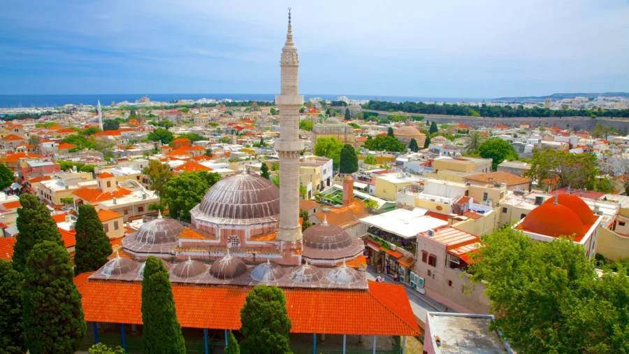 Aerial view of Rhodes coastal town with historic mosque and tall minaret by the sea.