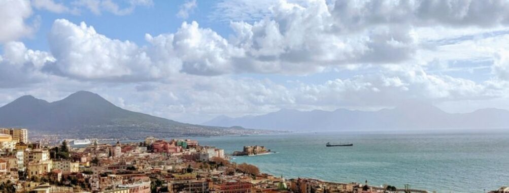 Aerial view of Naples, Italy with Mount Vesuvius, Mediterranean Sea, and vibrant architecture.