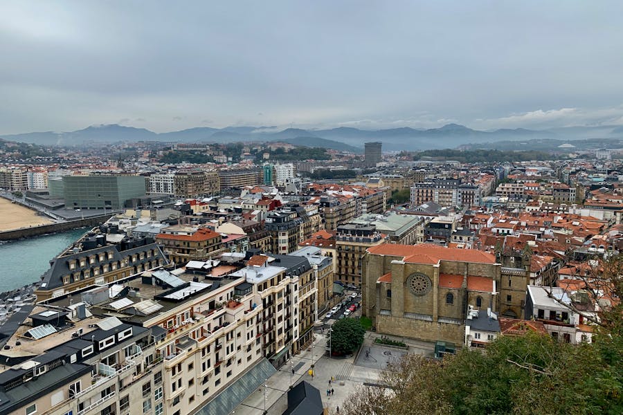 Aerial foggy coastal city panorama with European rooftops, church, and harbor.