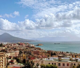 Aerial view of Naples, Italy with Mount Vesuvius, Mediterranean Sea, and vibrant architecture.