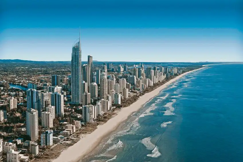 Aerial view of Broadbeach coastal city skyline with tall skyscrapers, sandy beach and blue ocean.