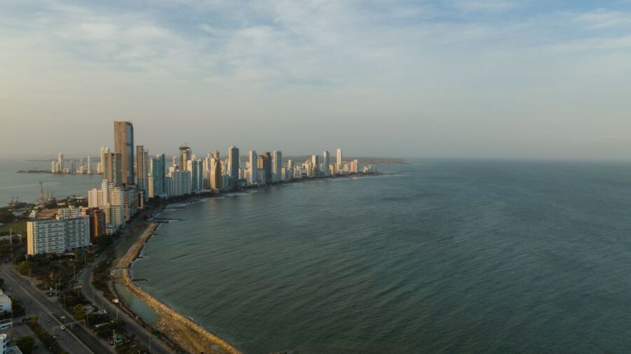 Aerial view of coastal city skyline with high-rises and sandy beach during sunset.