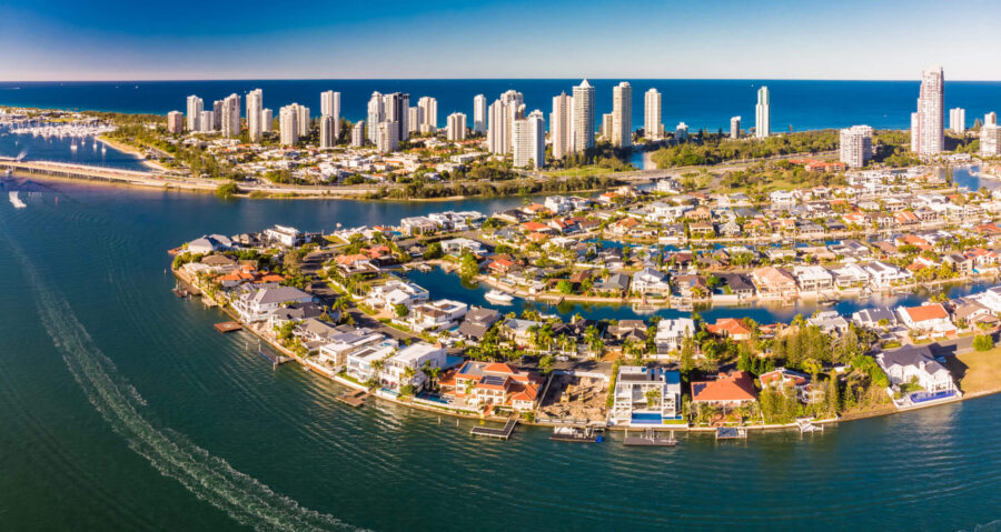 Aerial view of luxury coastal waterfront homes and high rise skyline by blue ocean.