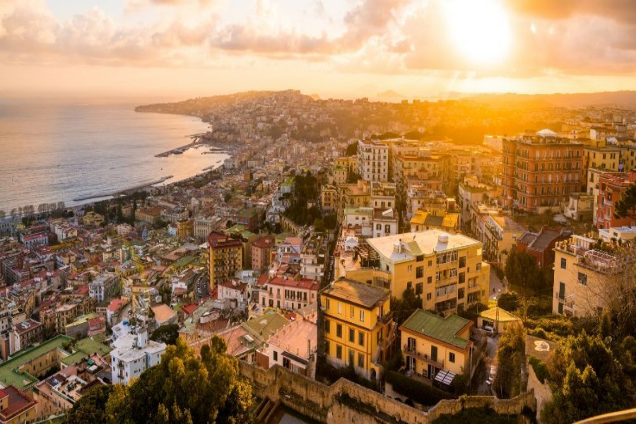 Mediterranean coastal city sunset panorama with terracotta rooftops and sea.