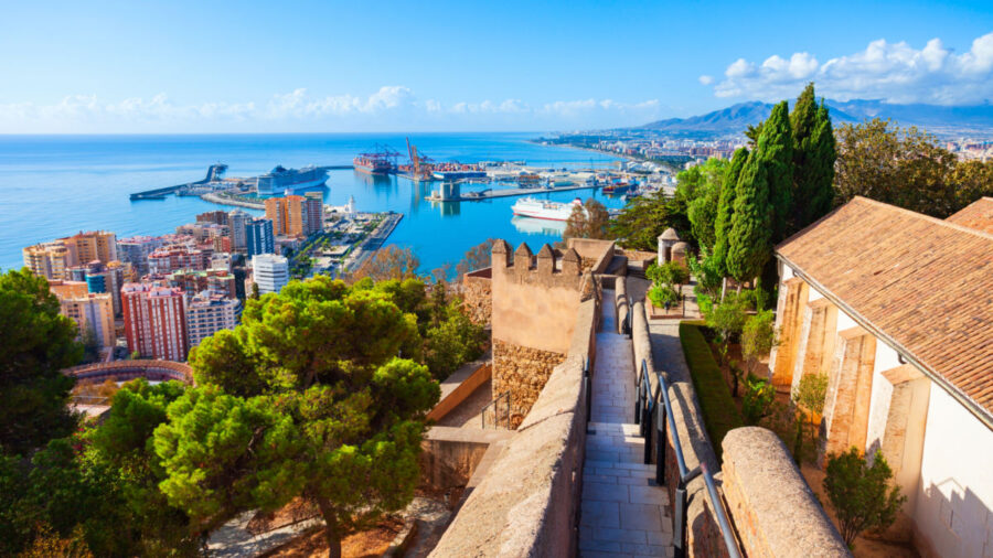 Panoramic view of Malaga: coastal city, Mediterranean Sea, vibrant architecture, lush greenery, mountains.